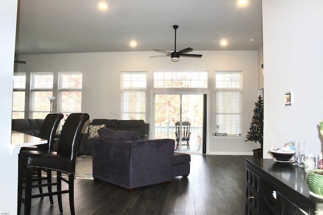 living area featuring dark wood-type flooring, plenty of natural light, a ceiling fan, and baseboards