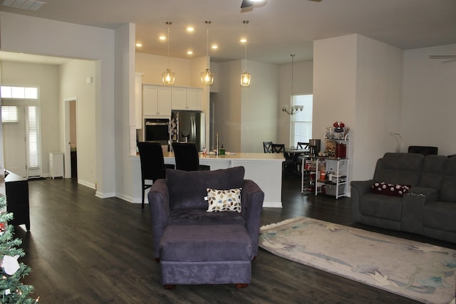 living area with recessed lighting, ceiling fan with notable chandelier, dark wood-type flooring, and baseboards