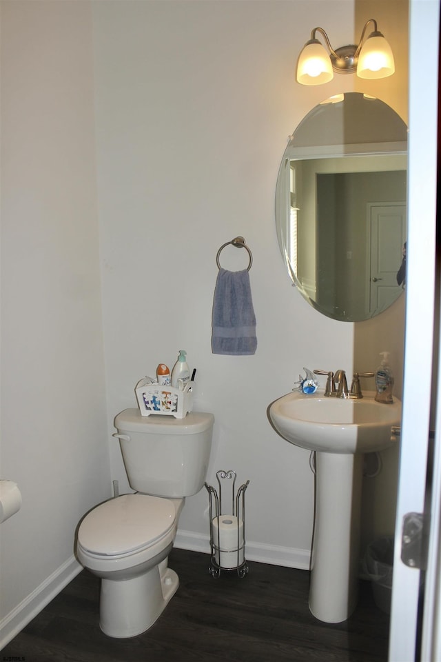 half bath featuring toilet, baseboards, and wood finished floors