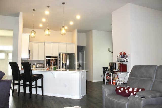 kitchen featuring a breakfast bar, a peninsula, dark wood-style flooring, stainless steel appliances, and white cabinets