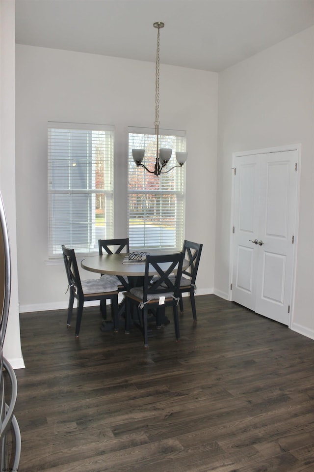 dining area featuring dark wood-type flooring, baseboards, and a chandelier