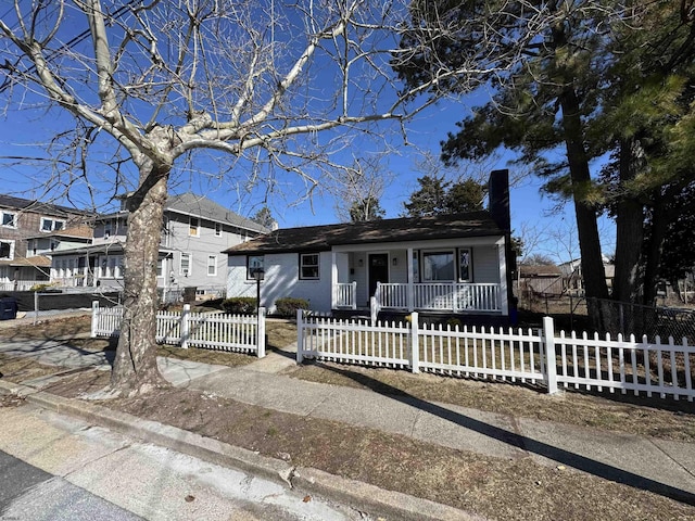 view of front facade featuring a fenced front yard, a porch, and a chimney