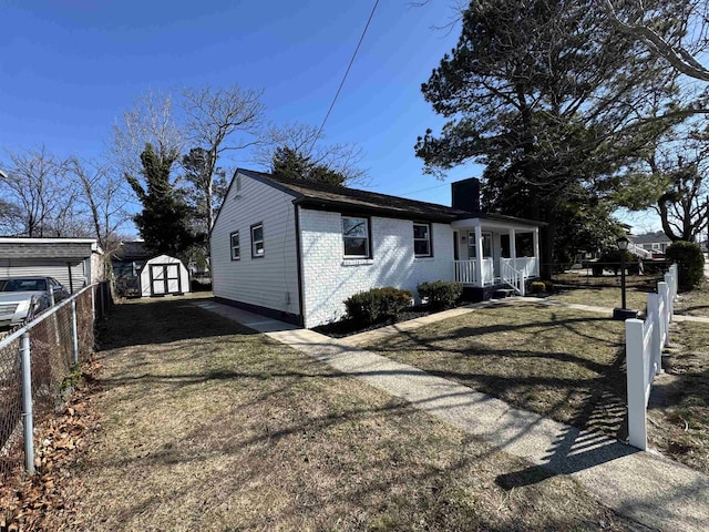 view of side of property featuring an outbuilding, fence, a storage shed, covered porch, and brick siding