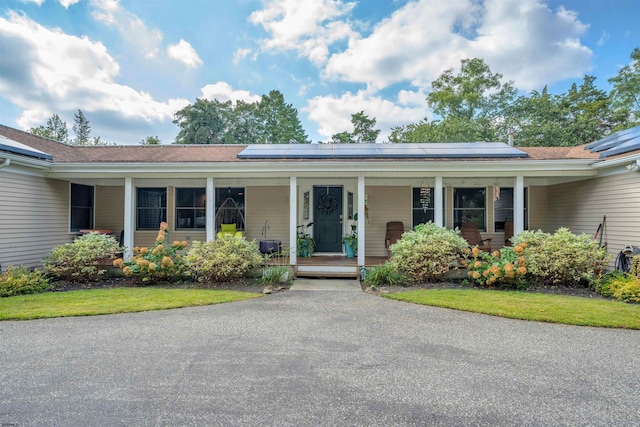 ranch-style house featuring covered porch and roof mounted solar panels