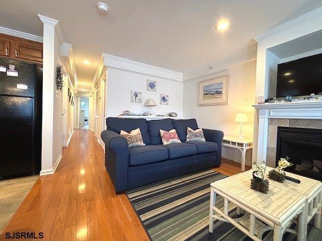 living room with a fireplace, baseboards, light wood finished floors, and ornamental molding