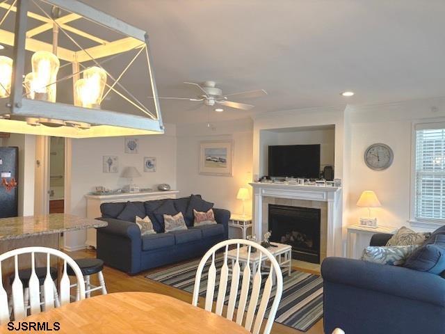 living area with a tiled fireplace, recessed lighting, ceiling fan, and wood finished floors