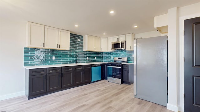 kitchen featuring light wood-type flooring, light countertops, appliances with stainless steel finishes, white cabinetry, and tasteful backsplash