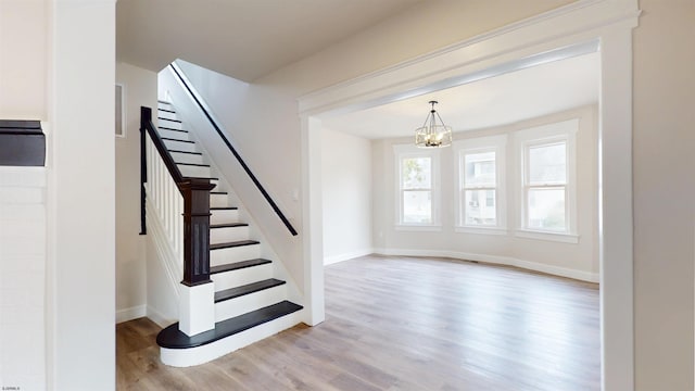 staircase with visible vents, baseboards, a notable chandelier, and wood finished floors