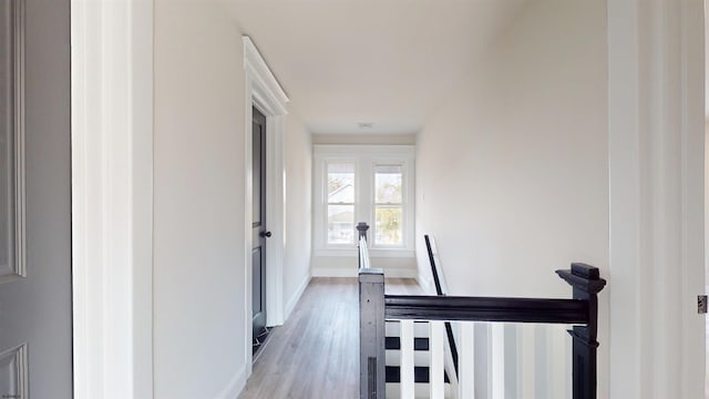 hall with baseboards, an upstairs landing, and wood finished floors