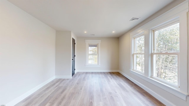 unfurnished room with a wealth of natural light, light wood-type flooring, and baseboards