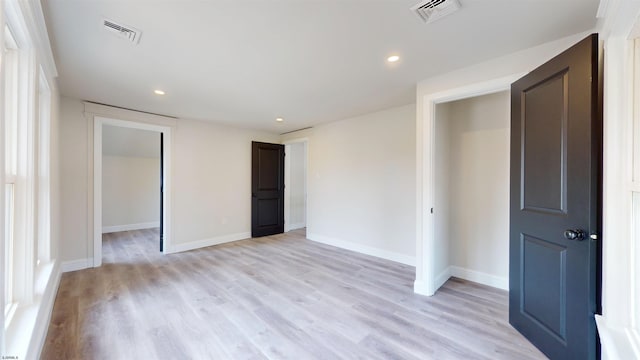 unfurnished bedroom with visible vents, light wood-type flooring, and baseboards