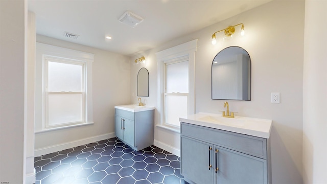 bathroom featuring two vanities, baseboards, visible vents, and a sink