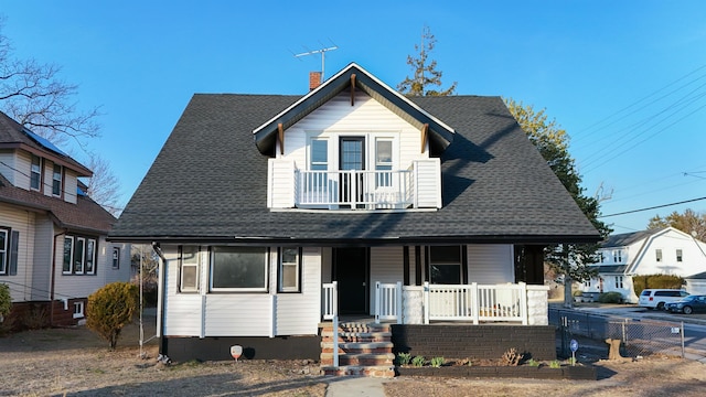 view of front of house featuring fence, roof with shingles, covered porch, a chimney, and a balcony