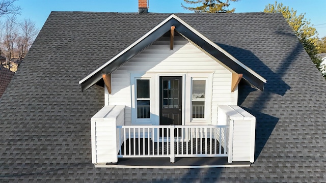 view of property exterior with a balcony, a chimney, and a shingled roof