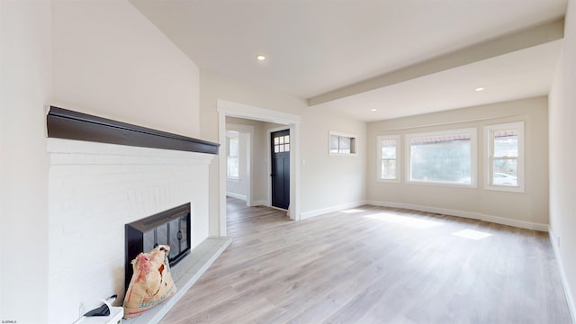 unfurnished living room featuring recessed lighting, baseboards, a brick fireplace, and light wood finished floors