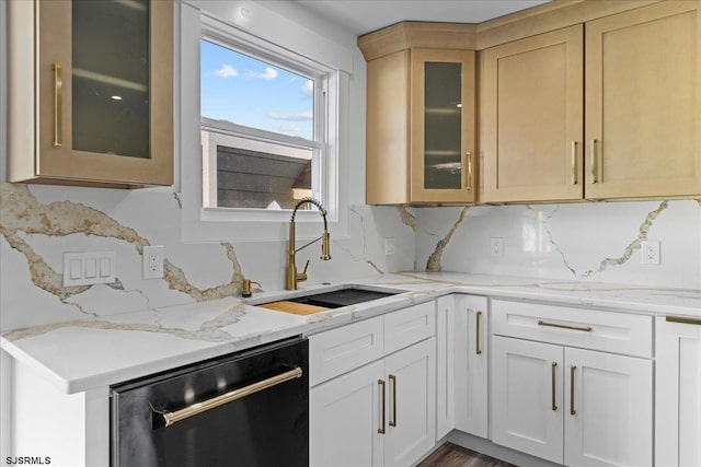 kitchen featuring backsplash, glass insert cabinets, dishwasher, light stone counters, and a sink