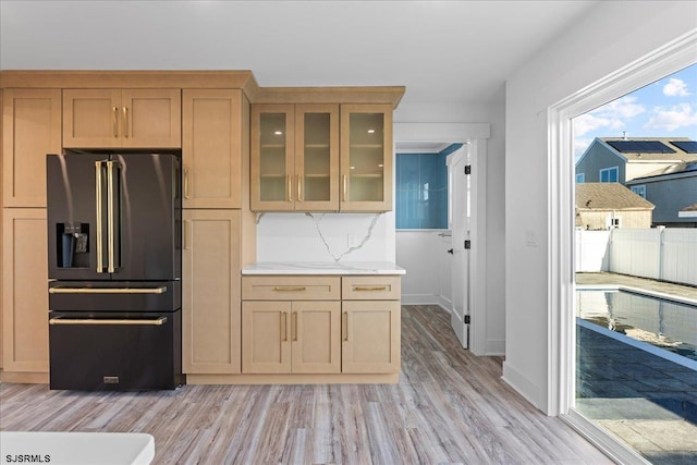 kitchen with glass insert cabinets, light wood-style flooring, high quality fridge, and baseboards