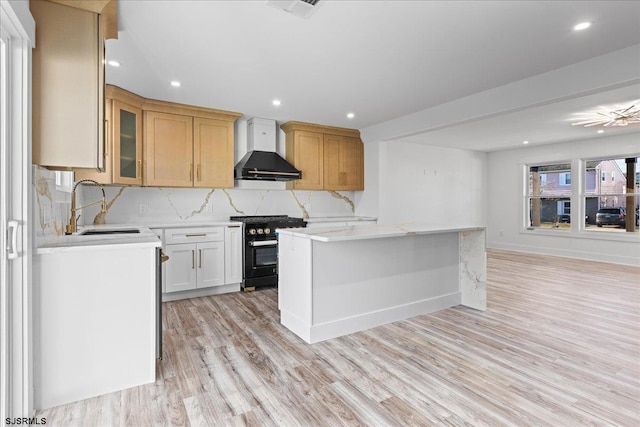 kitchen featuring light wood-style flooring, tasteful backsplash, a kitchen island, wall chimney exhaust hood, and stainless steel stove