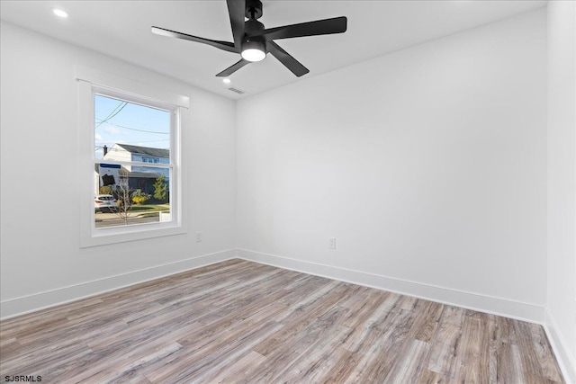 spare room with recessed lighting, light wood-style flooring, a ceiling fan, and baseboards