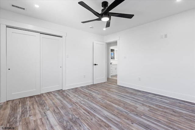 unfurnished bedroom featuring wood finished floors, visible vents, a closet, and baseboards