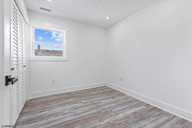 spare room with recessed lighting, visible vents, baseboards, and wood finished floors