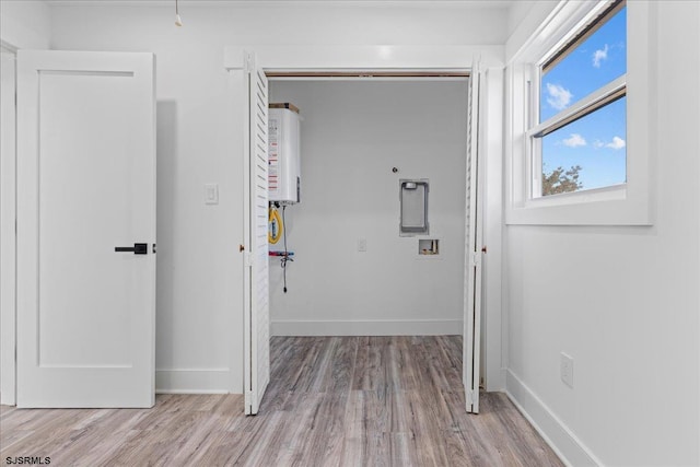 corridor with water heater, baseboards, and wood finished floors