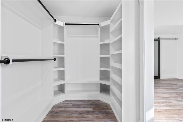 spacious closet featuring a barn door and wood finished floors