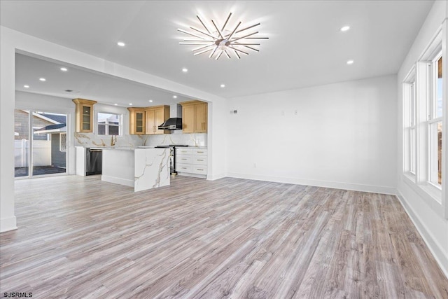 unfurnished living room featuring recessed lighting, baseboards, light wood-style floors, and a chandelier