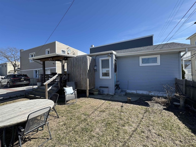 back of property with fence and a lawn