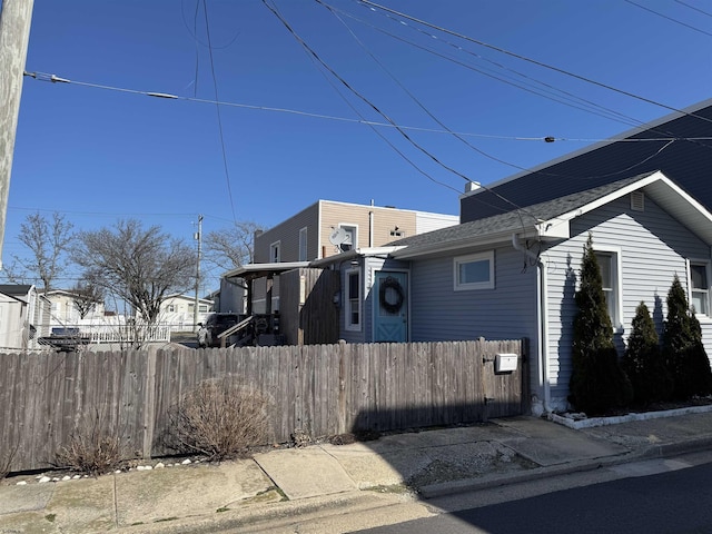 view of property exterior featuring fence and roof with shingles