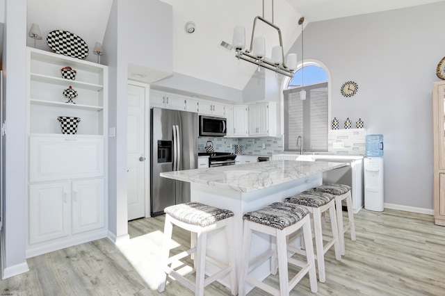 kitchen featuring a sink, stainless steel appliances, light stone countertops, and light wood-style flooring