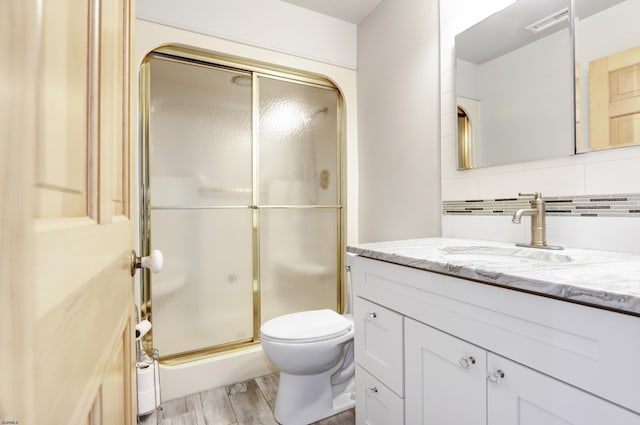 full bath with vanity, wood finished floors, a stall shower, toilet, and tasteful backsplash