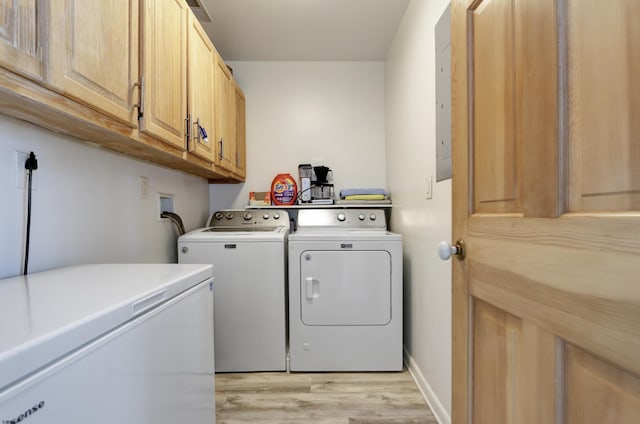 washroom featuring washing machine and clothes dryer, visible vents, electric panel, light wood-style flooring, and cabinet space