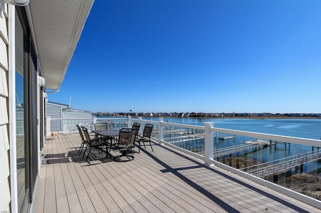 wooden terrace featuring outdoor dining space and a water view