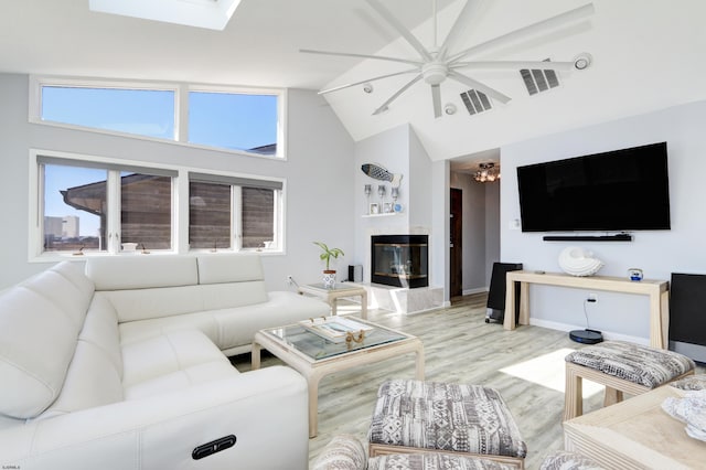 living room with visible vents, wood finished floors, high vaulted ceiling, and a glass covered fireplace