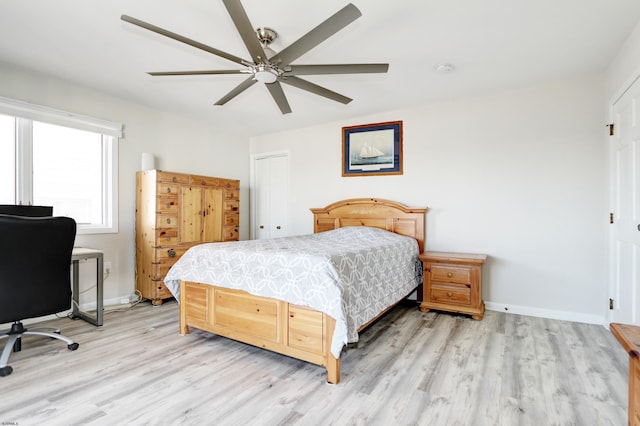 bedroom with light wood-style flooring, a ceiling fan, baseboards, and a closet