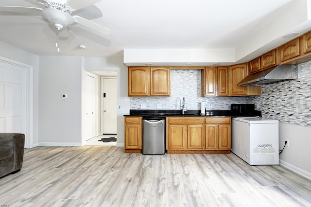 kitchen with a sink, under cabinet range hood, backsplash, light wood finished floors, and dishwasher