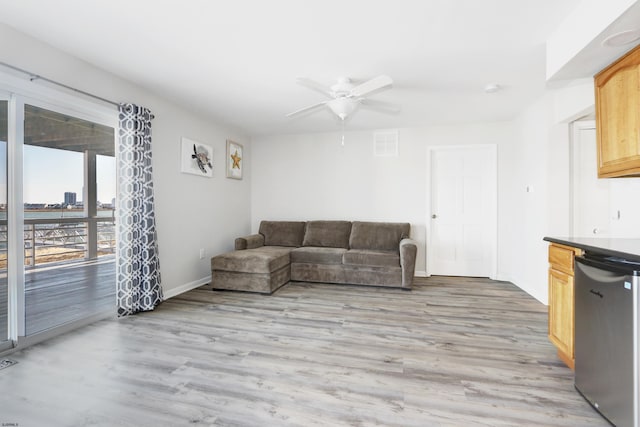 living area with visible vents, baseboards, light wood-style floors, and ceiling fan