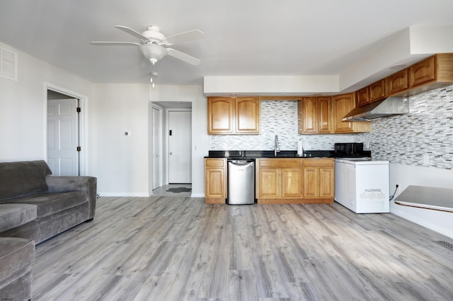 kitchen with decorative backsplash, stove, light wood-style floors, under cabinet range hood, and open floor plan