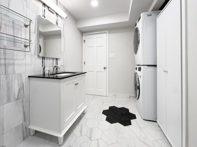 washroom featuring stacked washer / dryer and a sink