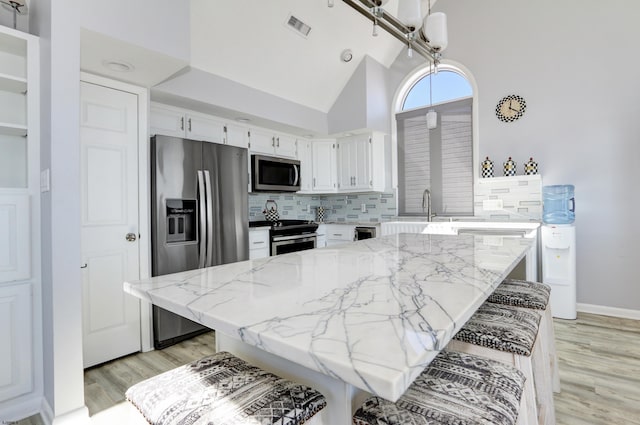 kitchen with visible vents, light stone counters, backsplash, appliances with stainless steel finishes, and white cabinets