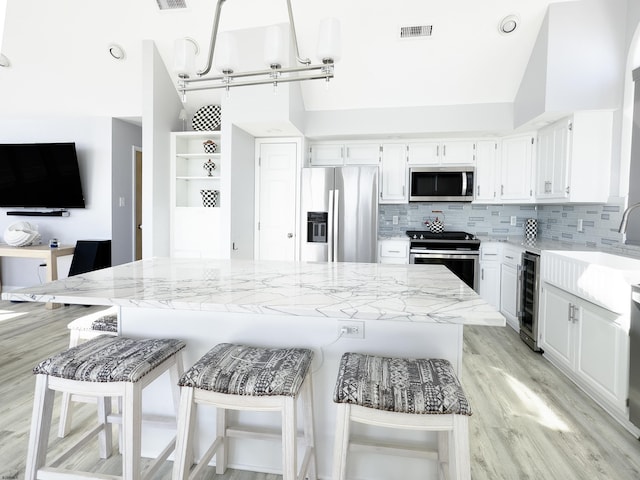 kitchen with visible vents, backsplash, white cabinetry, stainless steel appliances, and wine cooler