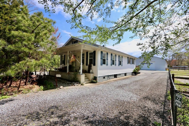 view of front of property with gravel driveway, covered porch, an outdoor structure, and fence