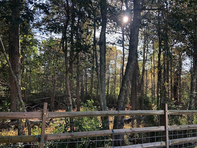 exterior space featuring a wooded view and fence