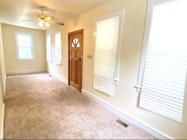 carpeted entrance foyer featuring a ceiling fan, baseboards, and visible vents