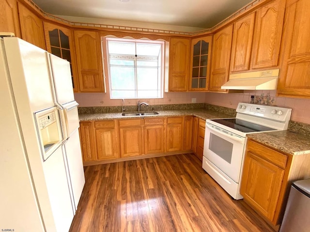 kitchen with brown cabinets, under cabinet range hood, a sink, wood finished floors, and white appliances