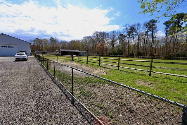 view of yard featuring a rural view, an outbuilding, a pole building, and fence