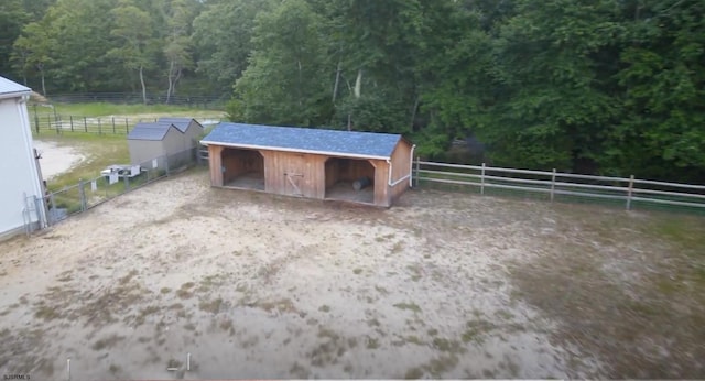 view of outbuilding with an outbuilding, a rural view, a wooded view, and an exterior structure