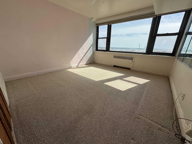 carpeted spare room with baseboards and radiator