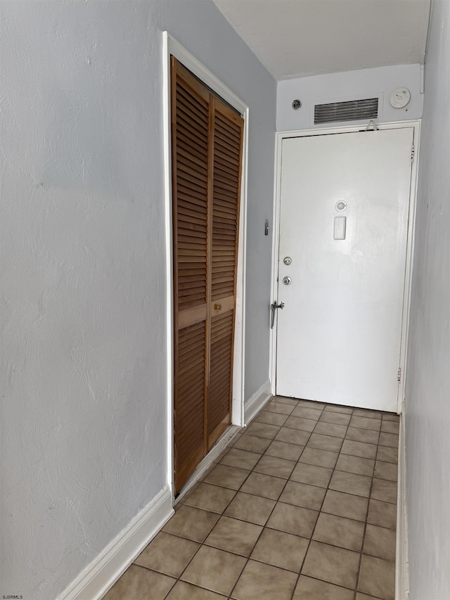 interior space featuring light tile patterned floors, visible vents, and baseboards